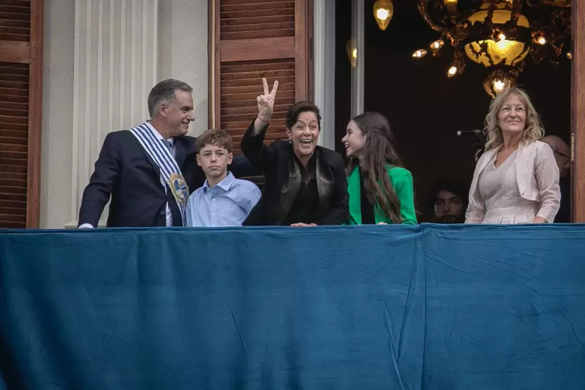Yamandú Orsi saludando en el balcón del Palacio Estévez junto a su familia y Carolina Cosse. Foto: Nicolás Garrido