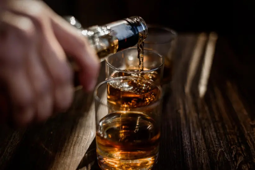 verter-bebidas-alcoholicas-fuertes-en-los-vasos-que-estan-sobre-la-mesa-de-madera