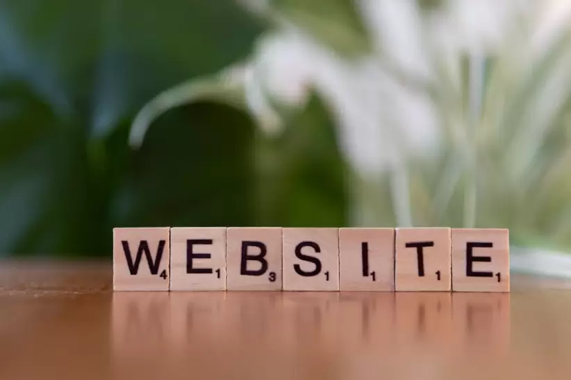 Fichas de Scrabble sobre una superficie de madera que forman la palabra 'Sitio web', que simboliza la comunicación digital.