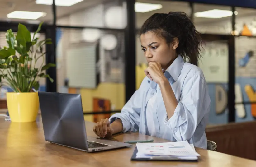 vista-lateral-de-la-mujer-que-trabaja-en-la-oficina-con-ordenador-portatil