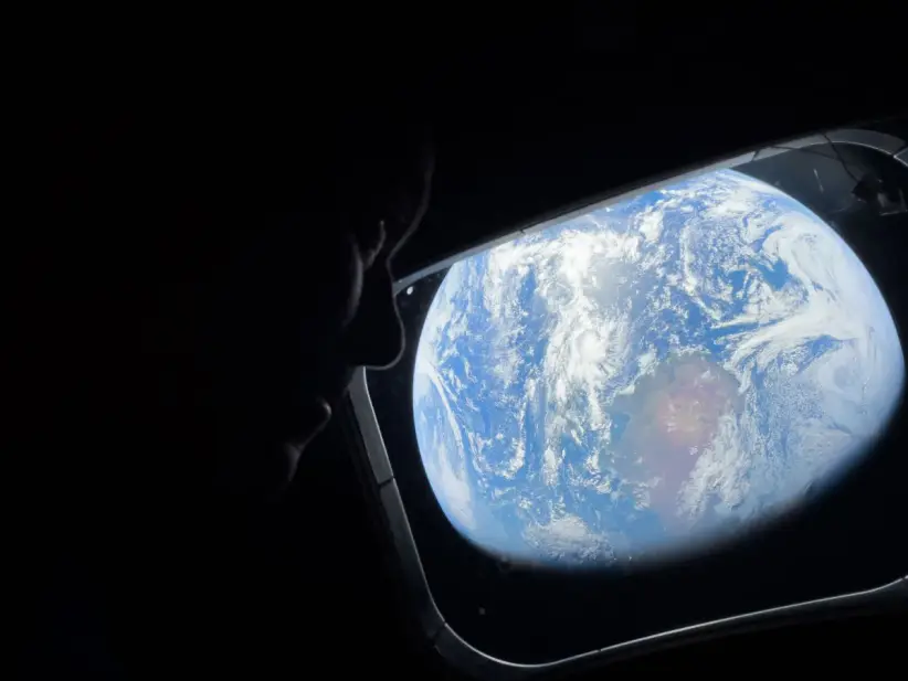 La astronauta  Christina Koch mirando la TIerra desde una de las ventanas del cohete espacial.