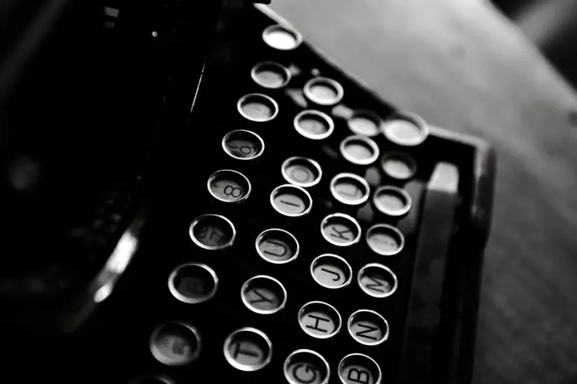 Fotografía clásica en blanco y negro de una máquina de escribir antigua que muestra sus teclas en detalle.